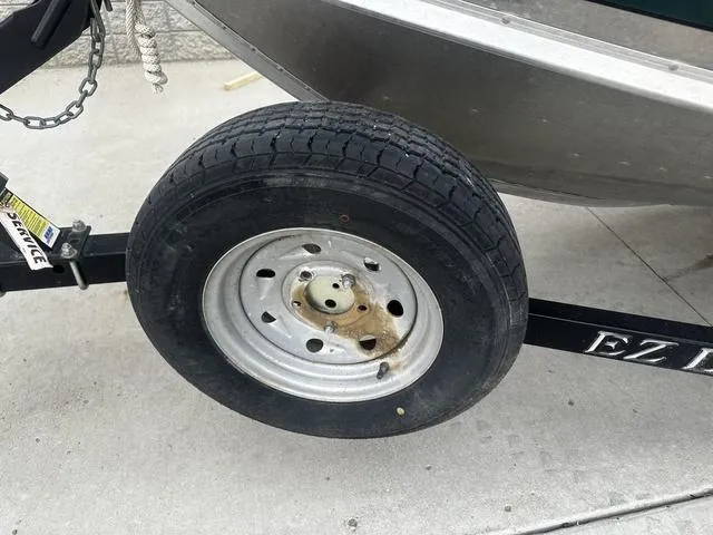 Slide: The Image of Trailer wheel of a 2005 Lund 16 REBEL boat on concrete surface. - 14