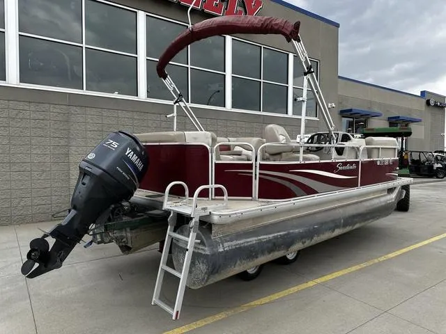 Slide: The Image of 2012 Godfrey Sweetwater pontoon boat with Yamaha motor, parked outside a building. - 2