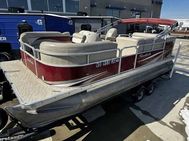 Slide: The Image of 2012 Godfrey Sweetwater pontoon boat with red and beige seating, parked on a trailer. - 4