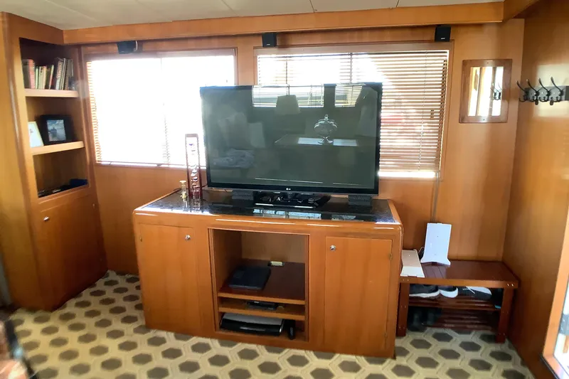 Slide: The Image of Interior of 1998 Grand Alaskan 60 Pilothouse with TV, wooden cabinetry, and patterned flooring. - 14