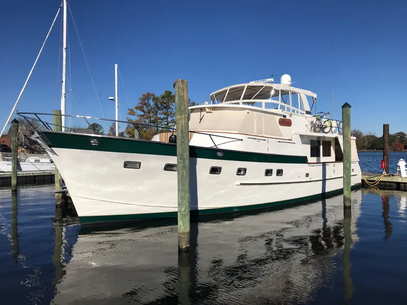 Slide: The Image of 1998 Grand Alaskan 60 Pilothouse yacht docked in a marina under clear blue skies. - 2
