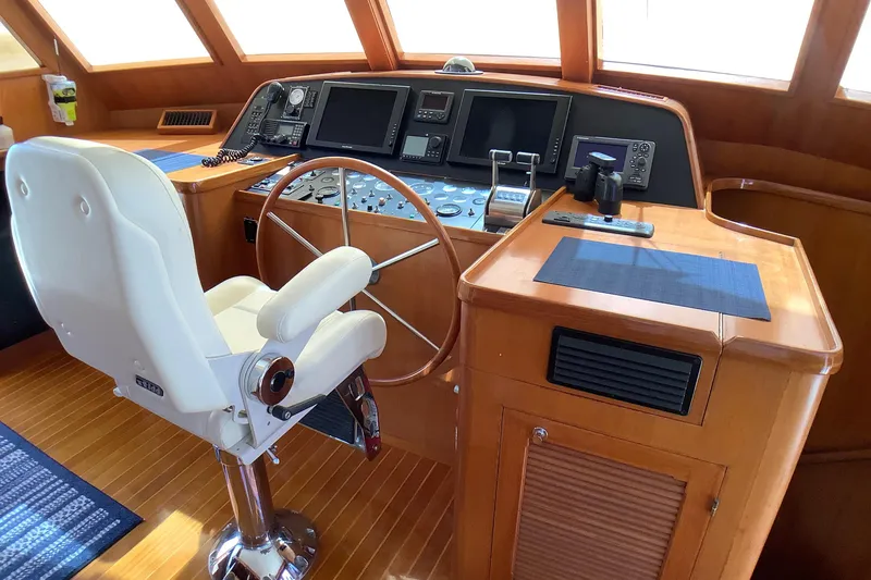 Slide: The Image of Pilothouse of 1998 Grand Alaskan 60, featuring a steering wheel and navigation controls. - 23