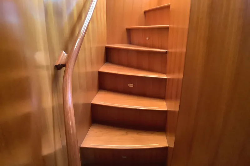 Slide: The Image of Wooden staircase inside 1998 Grand Alaskan 60 Pilothouse yacht, featuring curved handrail. - 31