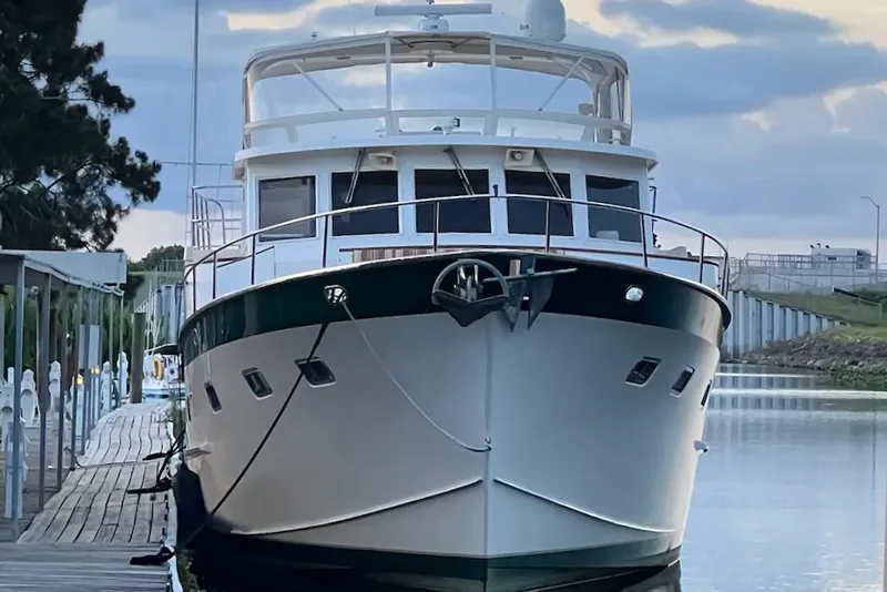 Slide: The Image of 1998 Grand Alaskan 60 Pilothouse yacht docked at a serene marina. - 4