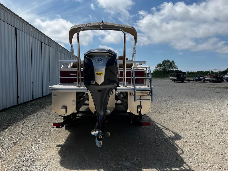 Slide: The Image of 2025 SunCatcher Fusion 324SS pontoon boat with outboard motor, parked on gravel. - 6