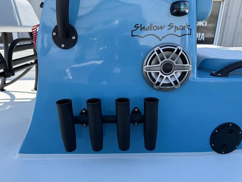 Slide: The Image of 2025 Shallow Sport 24 Modified V boat with rod holders and speaker on blue console. - 6