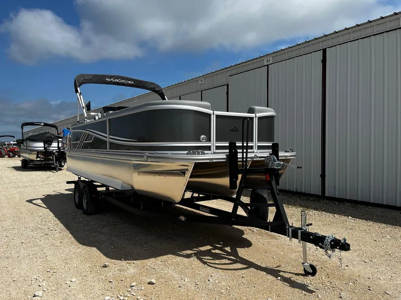 Slide: The Image of 2025 SunCatcher Fusion 324RC pontoon boat on trailer, parked outdoors under blue sky. - 1