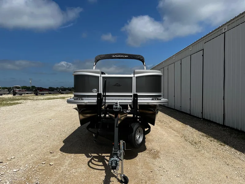Slide: The Image of 2025 SunCatcher Fusion 324RC pontoon boat on trailer, parked outdoors. - 2