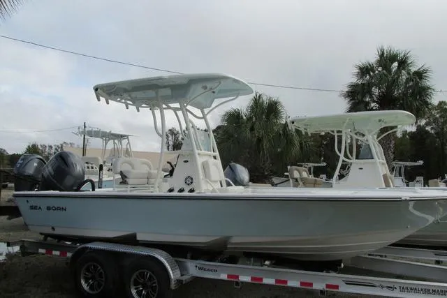 Slide: The Image of 2023 Sea Born FX22 boat on trailer, featuring dual engines and T-top, parked outdoors. - 2
