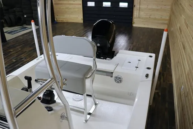 Slide: The Image of 2023 May-Craft 2200 Bay boat interior with seating and motor in a wooden garage. - 11