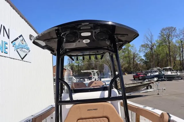 Slide: The Image of 2023 Sea Pro 219 Deep V Series boat with T-top and seating, parked outdoors. - 20