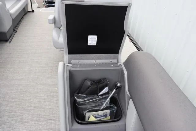 Slide: The Image of 2024 Bennington 22 SSR-SPS boat storage compartment with open lid, showing interior contents. - 25