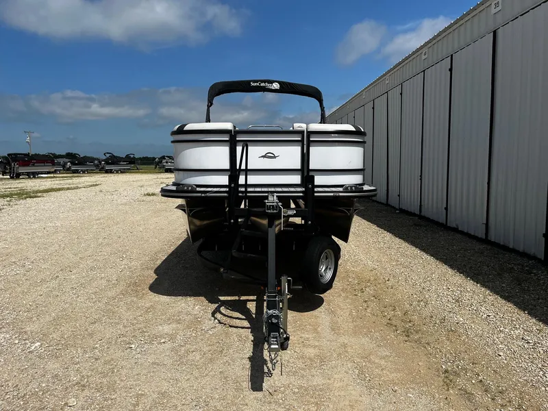 Slide: The Image of 2025 SunCatcher Select 322SS pontoon boat on trailer, parked outdoors. - 2
