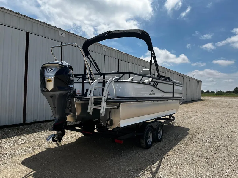 Slide: The Image of 2025 SunCatcher Select 322SS pontoon boat on trailer, parked outdoors under blue sky. - 7