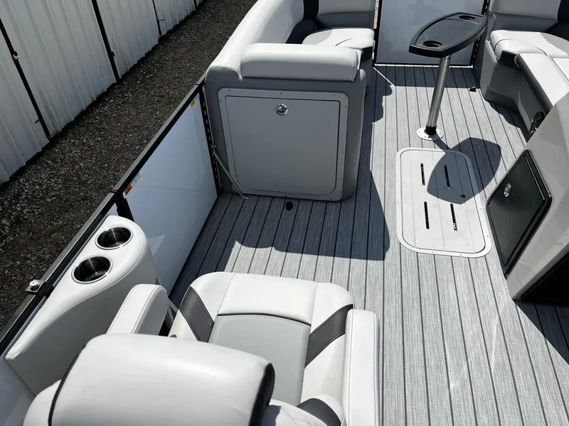 Slide: The Image of 2025 SunCatcher Select 322SS boat interior with gray seating and flooring, featuring cup holders and a table. - 9