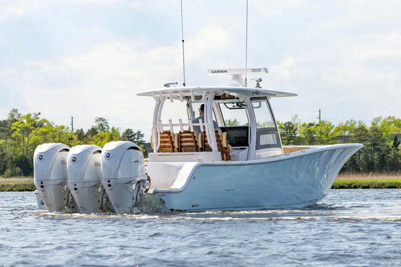 Slide: The Image of 2024 Sportsman Open 352 Center Console boat with triple engines on a calm waterway. - 12