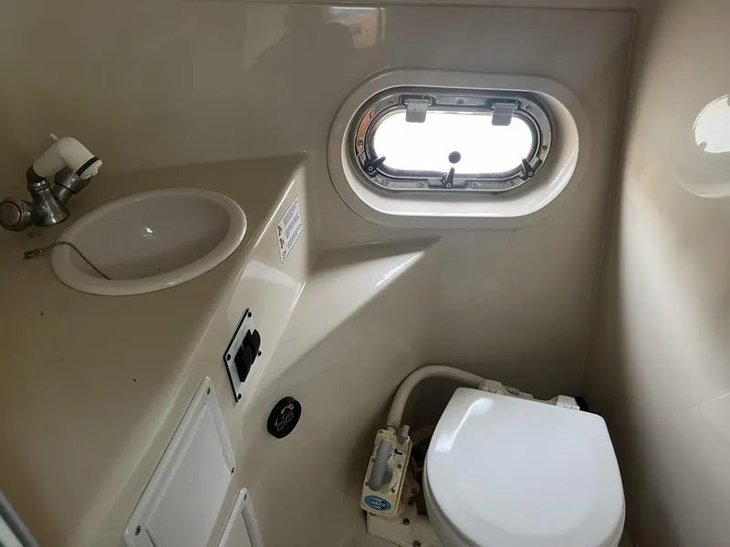 Slide: The Image of 2004 Four Winns 248 Vista boat bathroom with sink, toilet, and porthole window. - 17