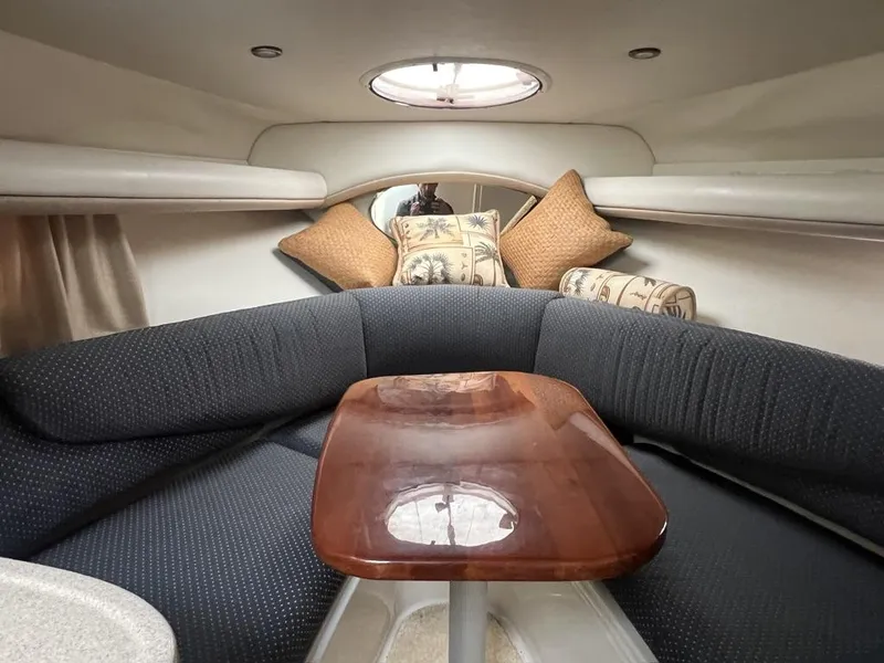 Slide: The Image of 2004 Four Winns 248 Vista cabin interior with cushioned seating and wooden table. - 18