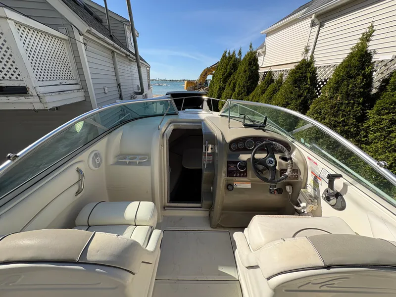 Slide: The Image of 2007 Sea Ray 215 Weekender boat interior with steering wheel and seating, docked near waterfront homes. - 11