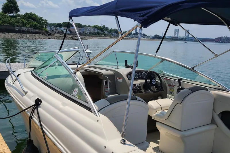 Slide: The Image of 2007 Sea Ray 215 Weekender boat docked by the water, featuring a sleek interior design. - 20