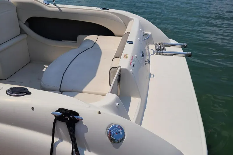 Slide: The Image of 2007 Sea Ray 215 Weekender boat interior with seating and swim ladder on calm water. - 21