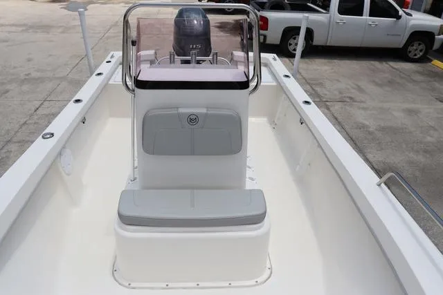 Slide: The Image of 2023 May-Craft 1900 CC boat interior with console and seating, parked near vehicles. - 10