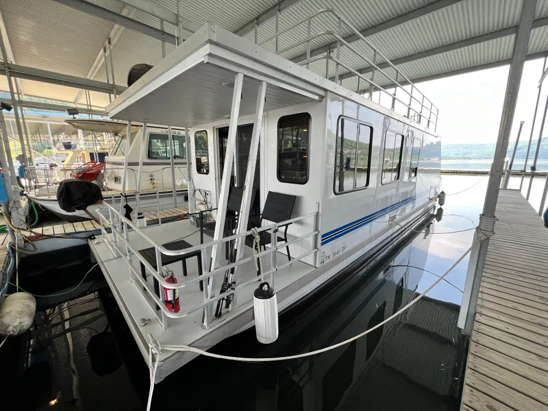 Slide: The Image of 2021 Catamaran Cruisers 39 x 12 houseboat docked under a covered marina. - 0