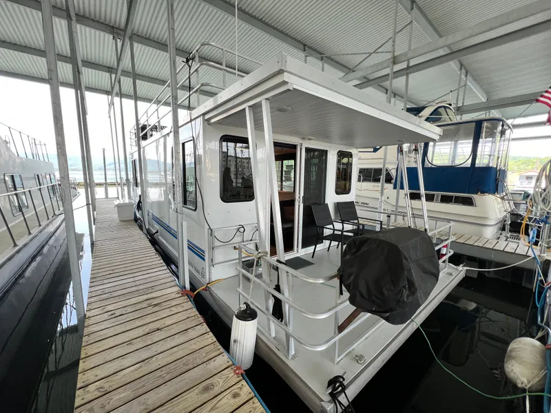 Slide: The Image of 2021 Catamaran Cruisers 39 x 12 houseboat docked in a marina, featuring outdoor seating. - 1