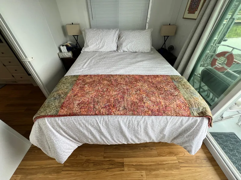Slide: The Image of Cozy bedroom in 2021 Catamaran Cruisers houseboat with colorful quilt and wooden flooring. - 10