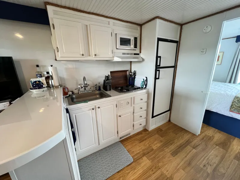 Slide: The Image of Modern kitchen in 2021 Catamaran Cruisers 39 x 12 houseboat with white cabinetry and wood flooring. - 5