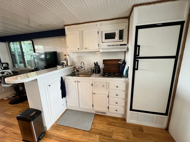 Slide: The Image of Modern kitchen in 2021 Catamaran Cruisers 39 x 12 houseboat with white cabinetry and appliances. - 6
