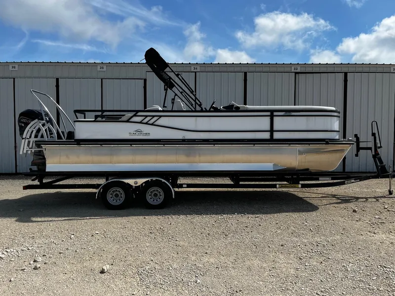 Slide: The Image of 2025 SunCatcher Select 324SS pontoon boat on trailer, parked outdoors under blue sky. - 0