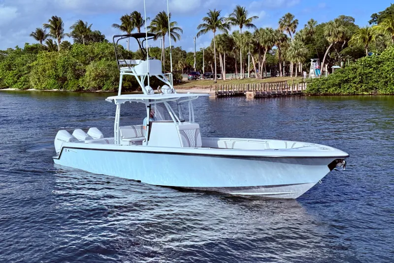 Slide: The Image of 2024 Contender 39 ST boat cruising on a scenic waterway with palm trees in the background. - 2