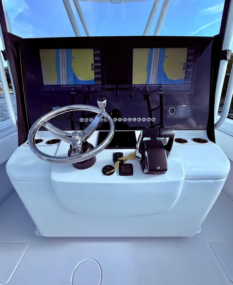 Slide: The Image of 2024 Contender 39 ST boat dashboard with dual navigation screens and steering wheel. - 21