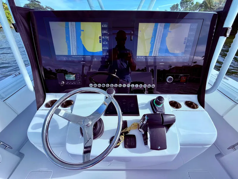 Slide: The Image of 2024 Contender 39 ST boat dashboard with dual navigation screens and steering wheel. - 24