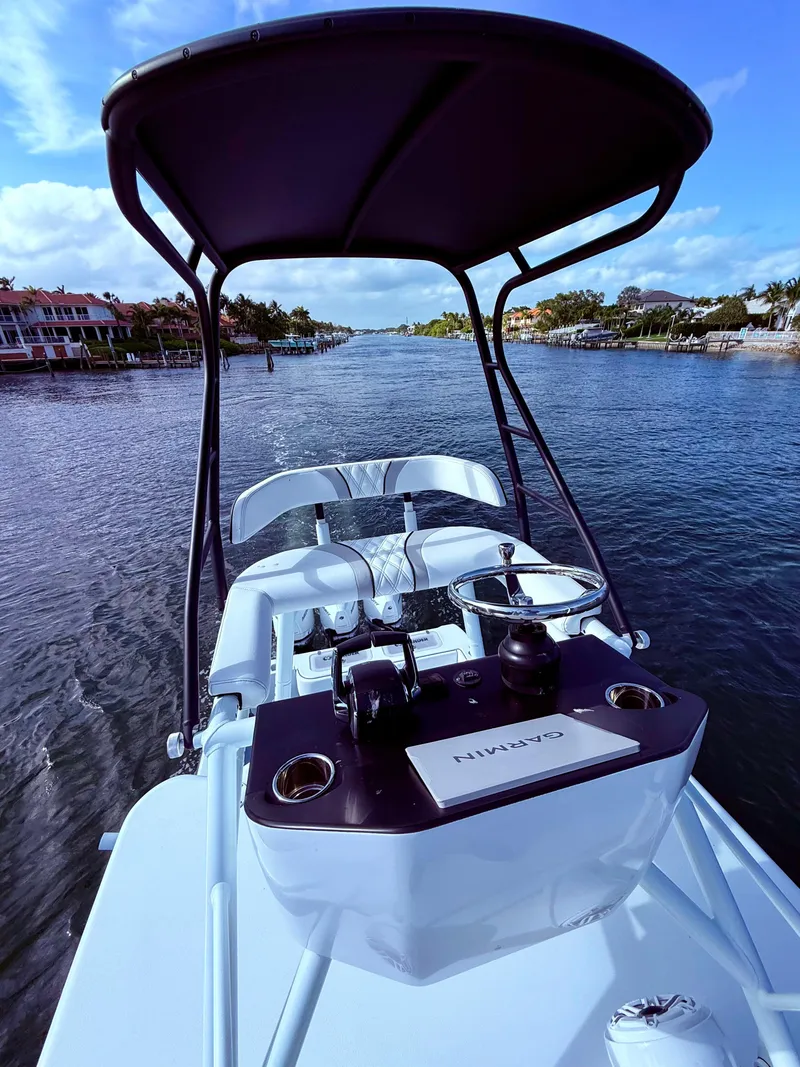 Slide: The Image of 2024 Contender 39 ST boat on a scenic waterway, featuring a sleek helm and canopy. - 28