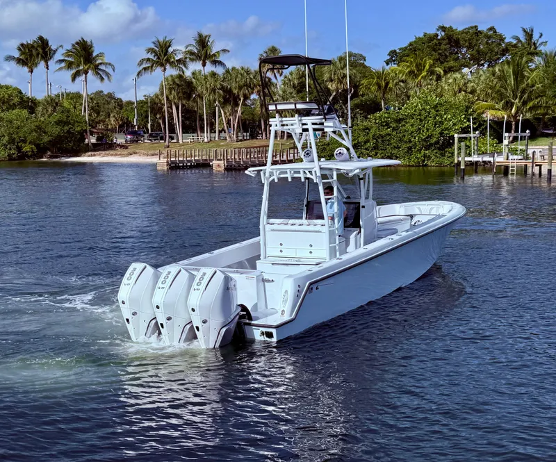 Slide: The Image of 2024 Contender 39 ST boat with triple engines cruising on a tropical waterway. - 3