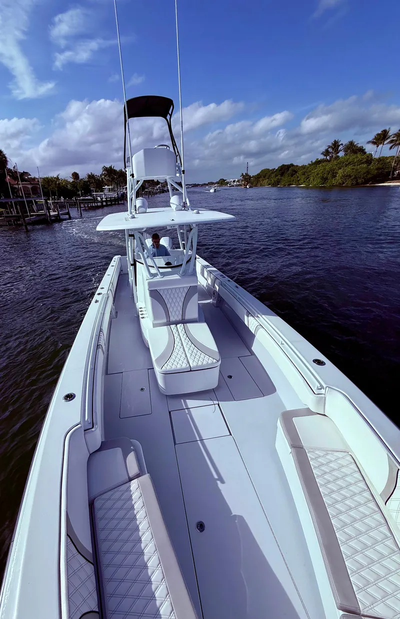 Slide: The Image of 2024 Contender 39 ST boat cruising on a scenic waterway under a clear blue sky. - 5