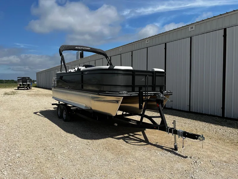 Slide: The Image of 2025 SunCatcher Select 322RC pontoon boat on trailer, parked outdoors near storage units. - 1