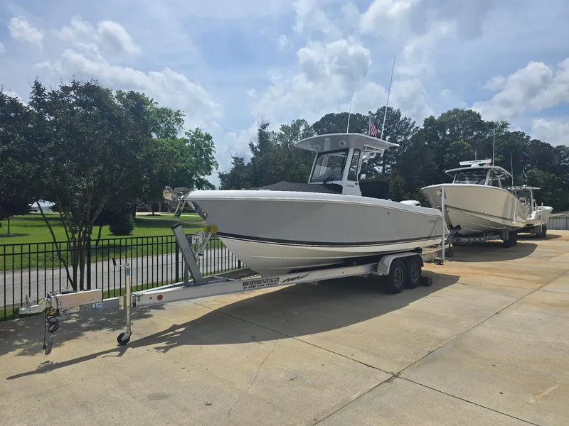 Slide: The Image of 2025 Pursuit S 248 Sport boat on trailer, parked outdoors under a cloudy sky. - 1