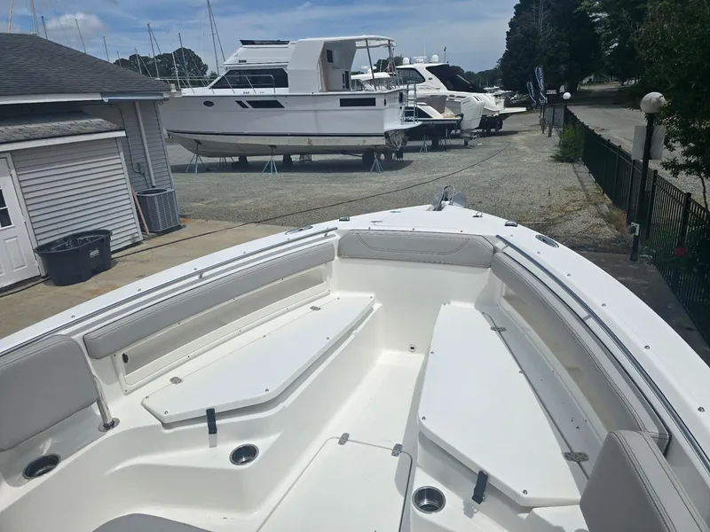 Slide: The Image of 2025 Pursuit S 248 Sport boat with spacious seating, docked near other vessels. - 8