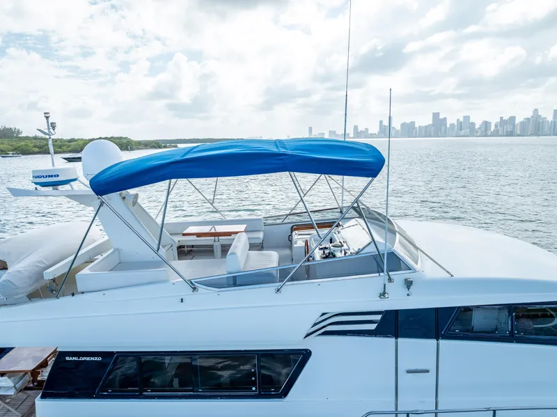 Slide: The Image of Sanlorenzo 62 yacht, 1995 model, with blue canopy, cruising near city skyline. - 15