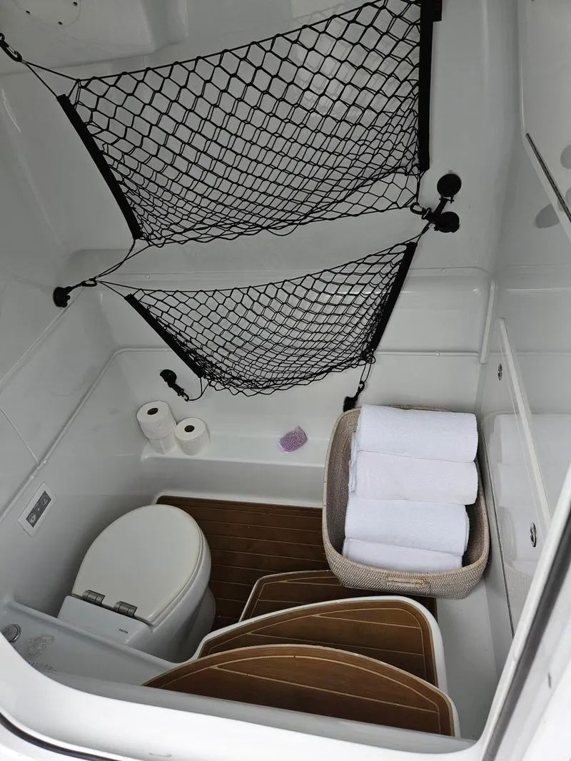 Slide: The Image of 2022 Yellowfin 39 Offshore boat bathroom with toilet, storage nets, and towels. - 20