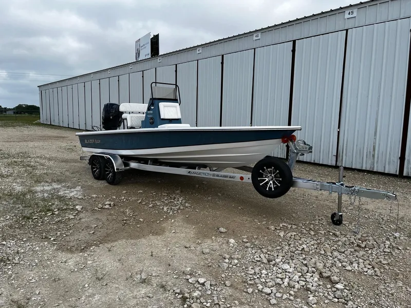 Slide: The Image of 2025 Blazer Bay 2220 Fisherman boat on trailer, parked near storage units. - 2