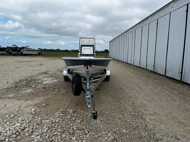 Slide: The Image of 2025 Blazer Bay 2220 Fisherman boat on trailer, parked on gravel near a large building. - 3