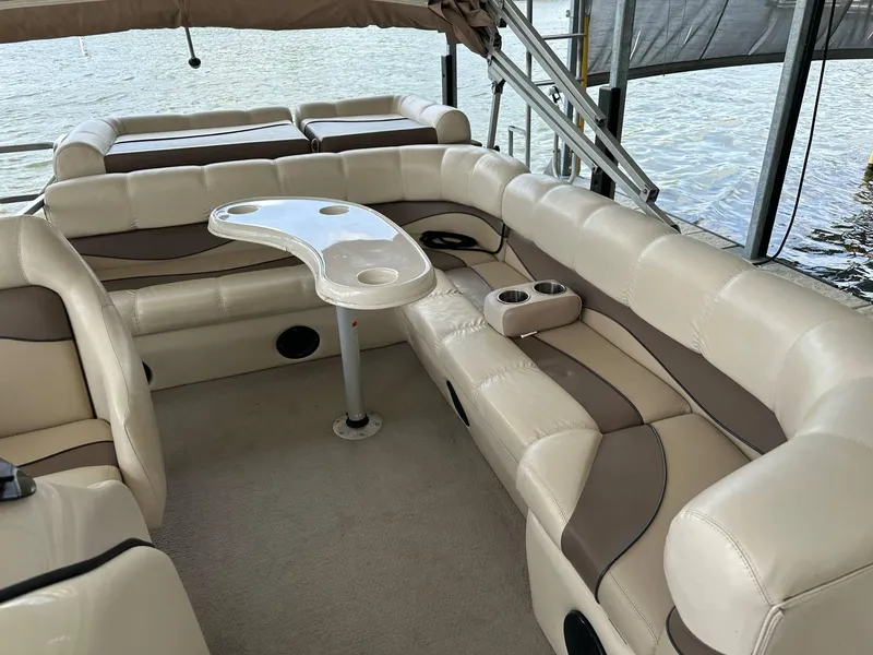 Slide: The Image of 2004 PlayCraft 2500 Ultra pontoon boat interior with beige seating and a central table. - 12