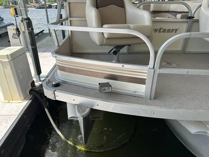 Slide: The Image of 2004 PlayCraft 2500 Ultra pontoon boat docked, showing rear seating and propeller. - 13
