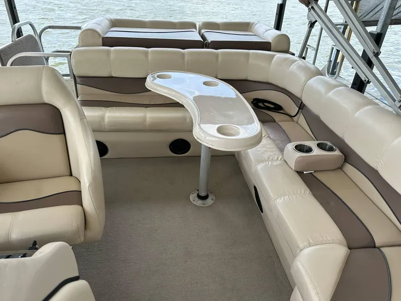 Slide: The Image of 2004 PlayCraft 2500 Ultra pontoon boat interior with beige seating and table. - 19
