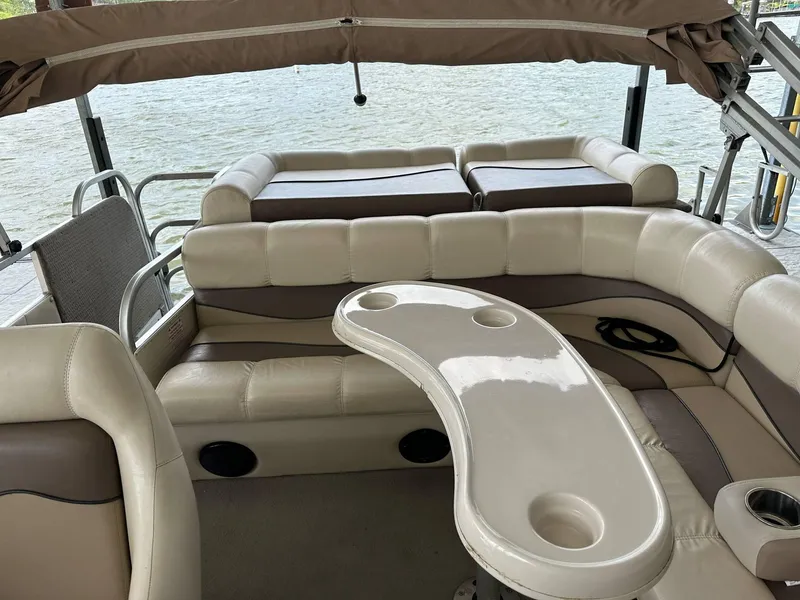 Slide: The Image of 2004 PlayCraft 2500 Ultra pontoon boat interior with beige seating and table, docked by water. - 20