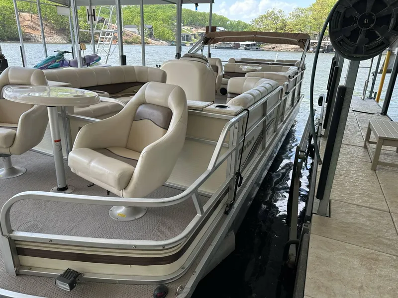 Slide: The Image of 2004 PlayCraft 2500 Ultra pontoon boat docked, featuring beige seating and a spacious deck. - 21
